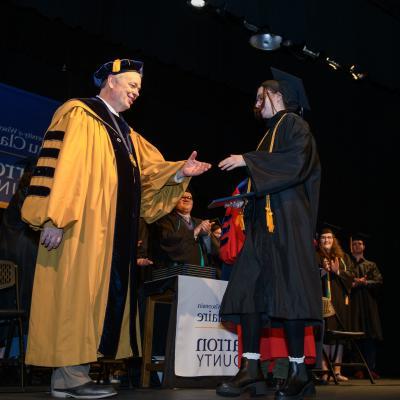 Chancellor Schmidt shaking graduate hand, Barron campus 